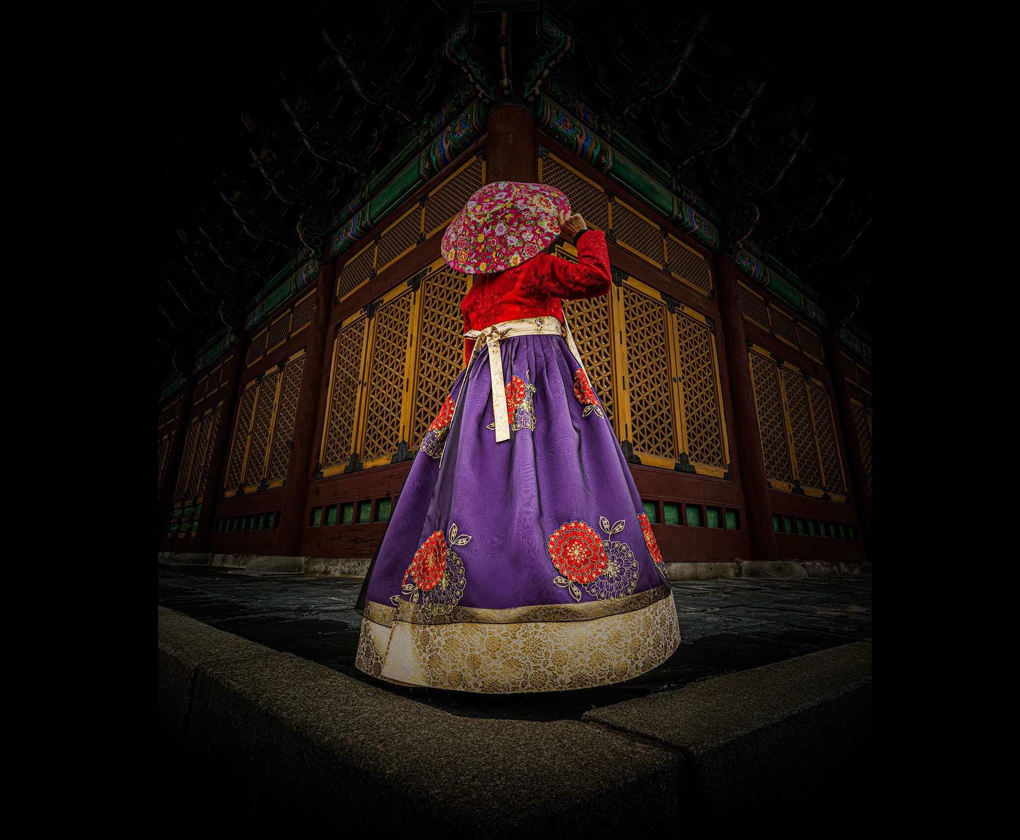 Woman in Red and Purple Hanbok standing in front of Deoksugung Palace in Seoul, Korea.