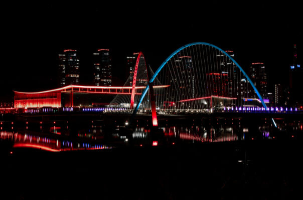 Daejeon Expo bridge and city scape at night illuminated in red and Blue across the river.